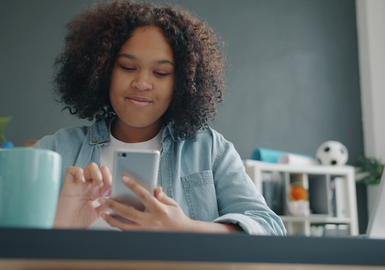 Young girl using a smartphone at a desk.