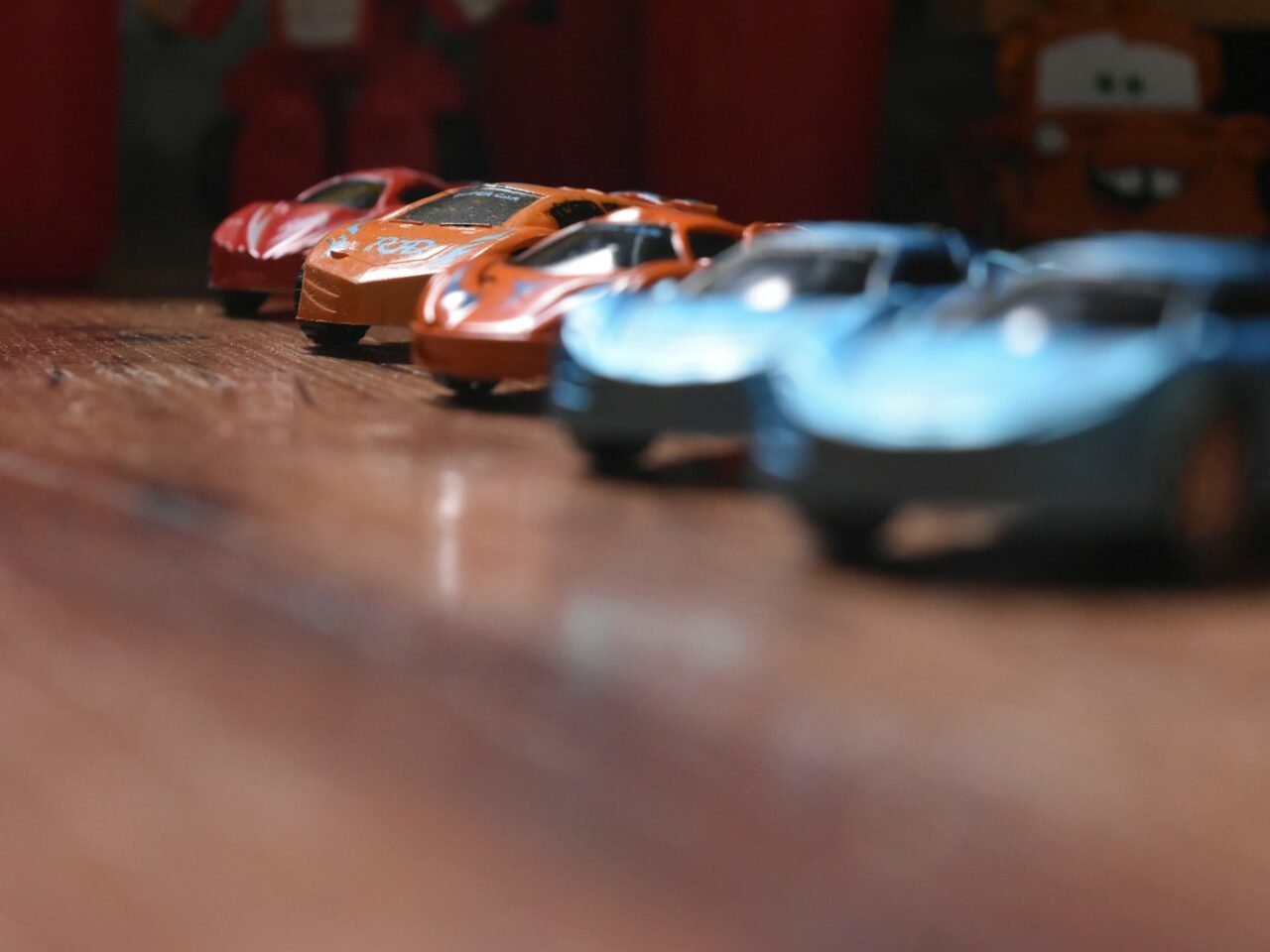 a row of toy cars sitting on top of a wooden floor