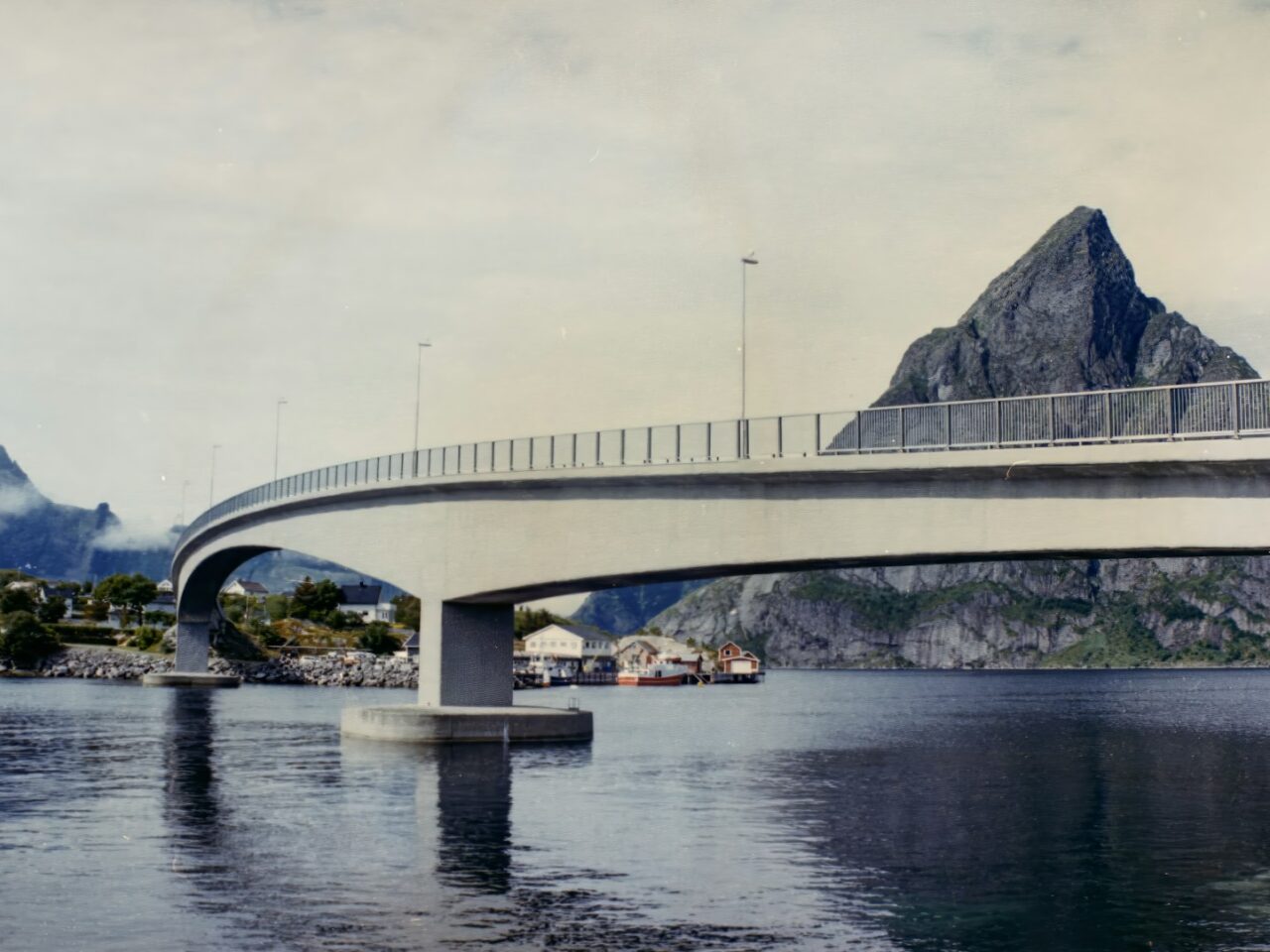 A bridge over a body of water with mountains in the background